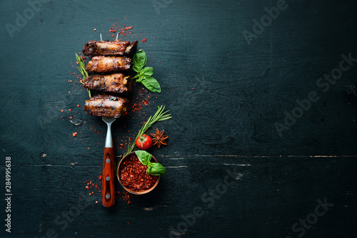 Pork ribs on the fork. On a wooden background. Top view. Free space for your text.