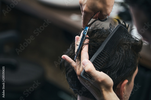 Barbershop. Close-up of man haircut, master does the hair styling in barber shop. Close-up, master Barber does the hairstyle and styling with scissors. Concept Barbershop.