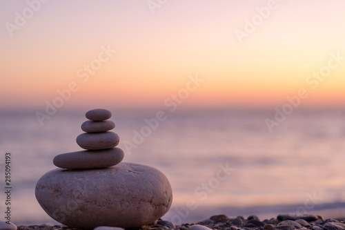 Perfect balance of stack of pebbles at seaside towards sunset. Concept of balance, harmony and meditation. Helping or supporting someone for growing or going higher up.