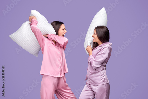 Young women having pillow fight during sleepover
