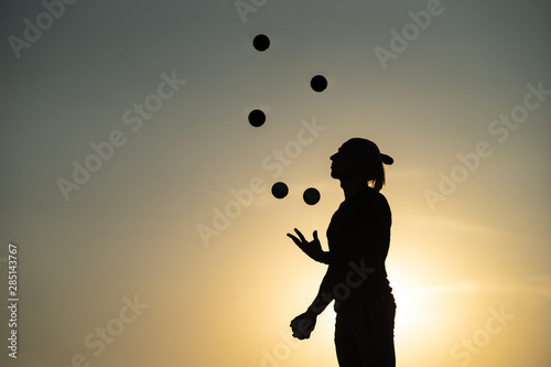 Silhouette of a man Juggling with Balls at Sunset