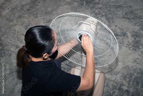 The housekeeper is assembling and installing an electric fan after cleaning..