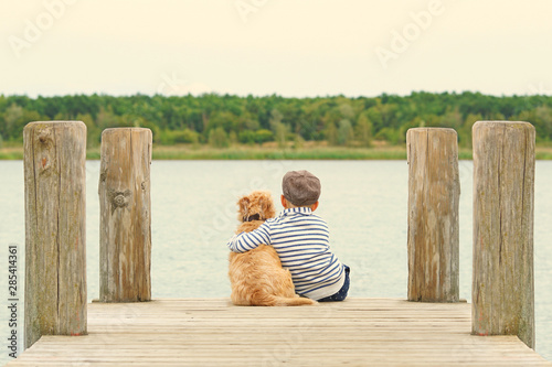 kleiner Junge mit seinem Hund am See