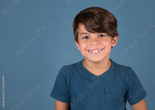 Handsome happy smiling boy in blue shirt isolated on blue background