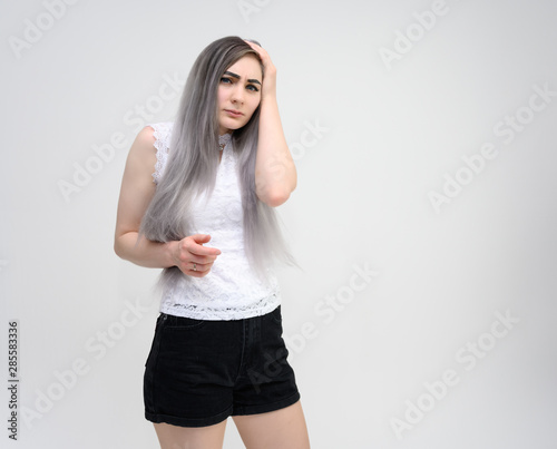 Studio portrait on the waist of a pretty manager girl with long beautiful hair in a white T-shirt and black shorts on a white background. He stands straight, smiles, shows with his hands.
