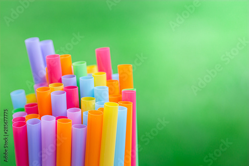 Multiple color drinking straws on a green grass background blur