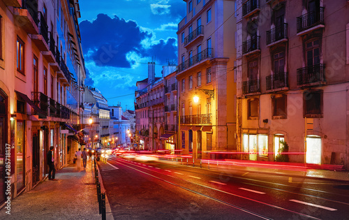 Porto, Portugal. Nighttime city life. Old town street with evening illumination and sky with clouds blue hour. Car speed lights on the road with asphalt.