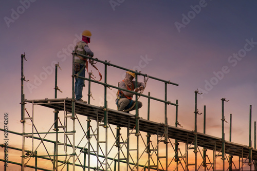 Man working on construction site with scaffold and building with sunset background,scaffolding for construction factory