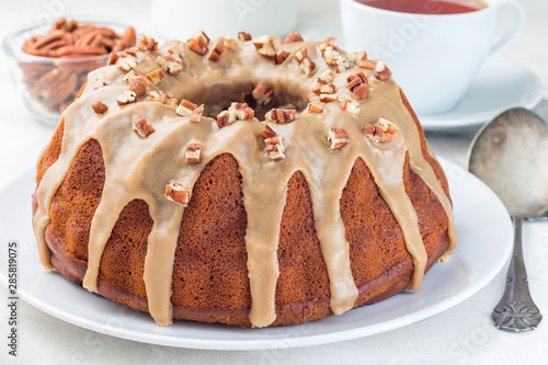 Sweet potato and pecan nuts pound cake with caramel icing on white plate, horizontal