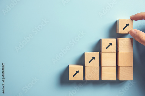 Business concept growth success process, Close up Woman hand arranging wood block stacking as step stair on paper blue background, copy space.