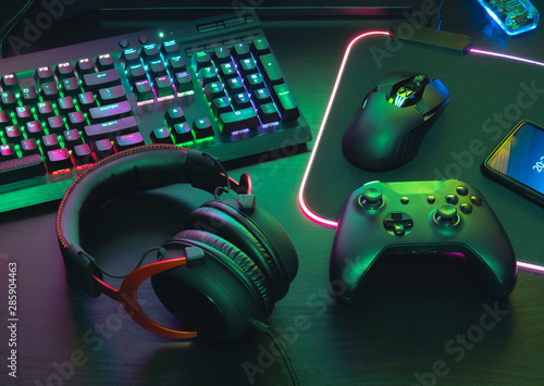 gamer work space concept, top view a gaming gear, mouse, keyboard, joystick, headset, mobile joystick, in ear headphone and mouse pad on black table background.