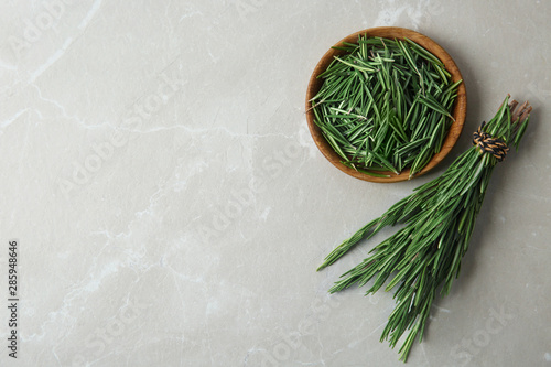 Plate and fresh rosemary twigs on grey marble background, flat lay. Space for text