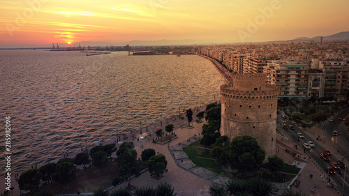 Aerial drone view of iconic historic landmark - old byzantine White Tower of Thessaloniki or Salonica at sunset with golden colours, North Greece