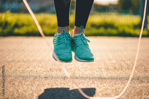 Sportswoman doing cardio exercises with skipping rope outdoors.