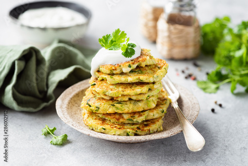 Vegetarian zucchini fritters or pancakes stack topped with sour cream and cilantro. Vegetable pancakes