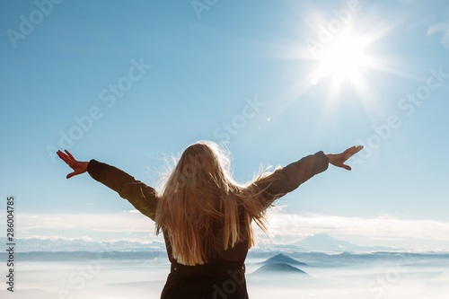 Beautiful happy woman enjoying mountains landscape with outstretched raised arms to the sky