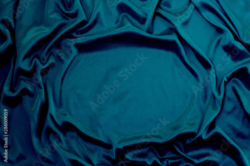 Photograph of silk fabric, color blue. The texture of silk fabric. Luxury silk fabric background with waves and drapery. Background for fashion luxury design, close-up, copy space