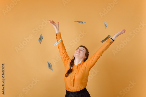A successful and happy woman throws money up for joy.