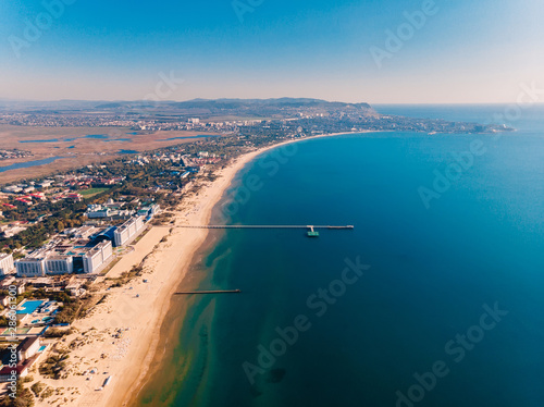 Aerial view of shore with pier, city and quit sea
