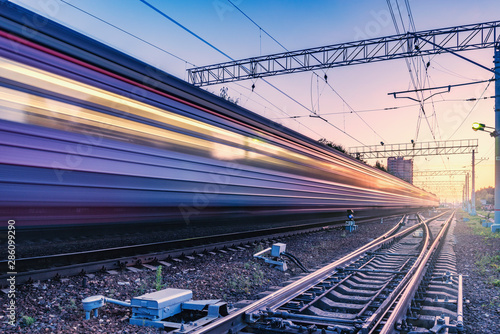 Passenger train moves fast at sunset time.