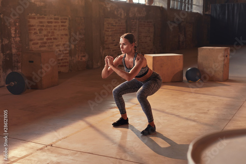 Fitness workout. Sport woman doing squat leg exercise at gym