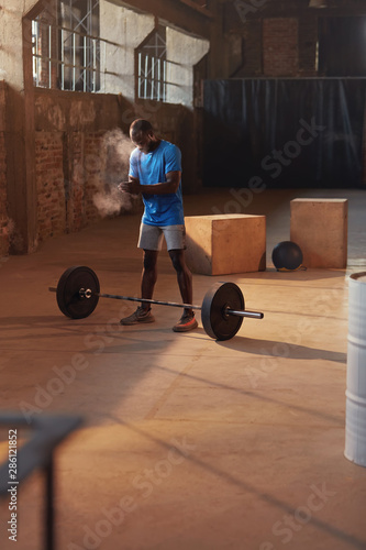 Sport man using hand chalk powder before workout at gym