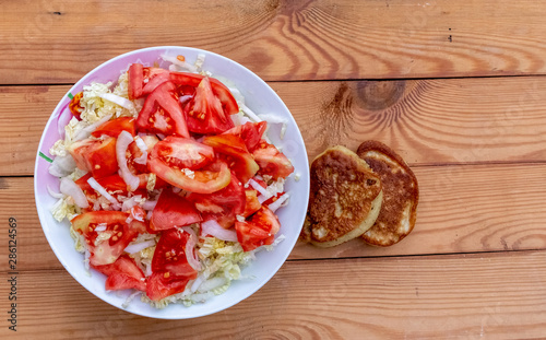 Sliced tomatoes, onions and cabbage on a plate on the table.