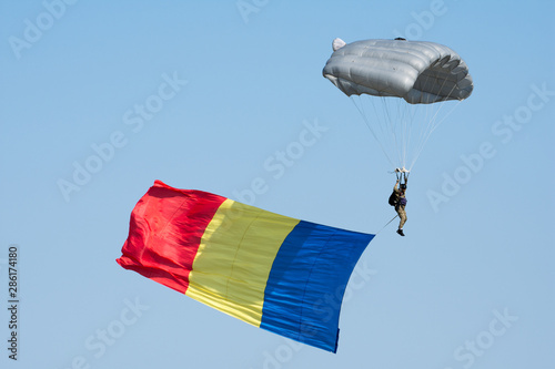 Bucharest, Romania - August 24 2019. Bucharest International Air Show BIAS 2019: Military paratrooper descending with the romanian flag 