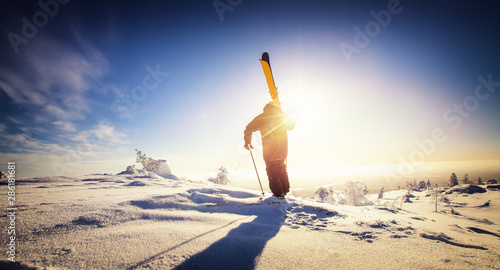 Skier stand mountain top with ski in hands. Winter extreme freeride concept