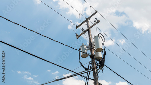 Power line pole with a transformer on it. Typical wooden post from USA