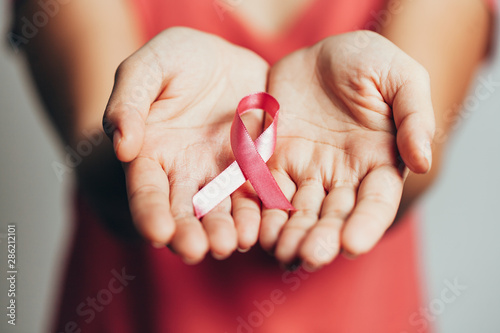 Healthcare and medicine concept - womans hands holding pink breast cancer awareness ribbon