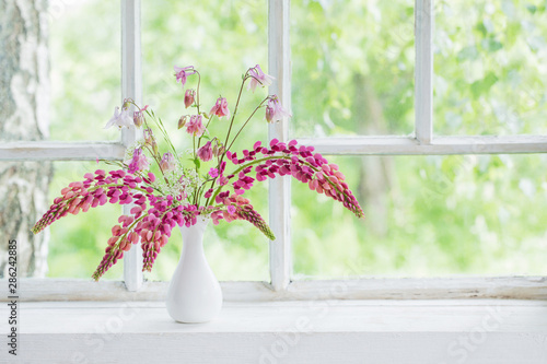 pink summer flowers in vase on white old windowsill