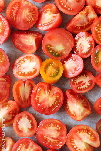 many red tomato slices on baking paper top view. cooking vegetables