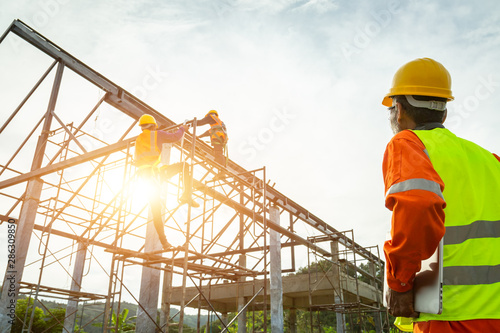 A construction worker control in the construction of roof structures on construction site and sunset background