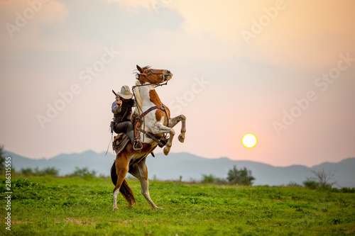 cowboy riding horse against sunset 