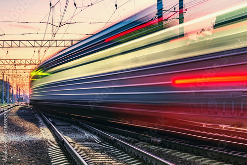 Passenger train moves fast at sunset time.