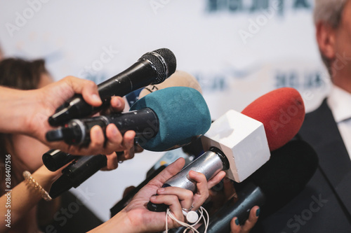 Details with the hands of journalists holding microphones in fron of a politician during a press conference