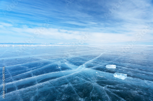 Winter landscape of frozen Baikal Lake. The endless fields of smooth blue ice and two transparent icicles on slippery ice surface. Cold natural background