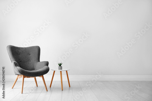 Stylish room interior with comfortable armchair near light wall, space for text