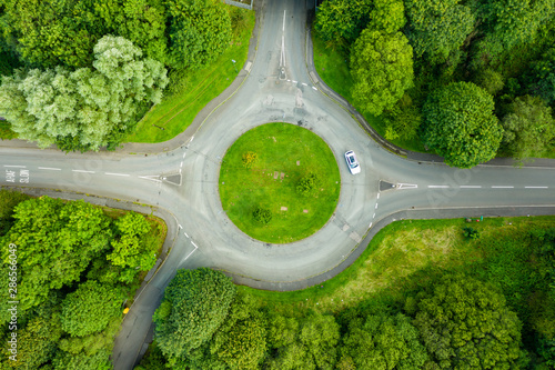 Top down aerial drone view of a small traffic roundabout on a quiet road