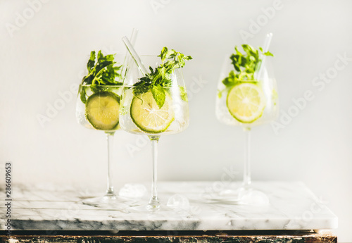 Hugo Sparkling wine cocktail with fresh mint and lime in glasses with eco-friendly straws over white marble counter, selective focus. Cold refreshing summer alcoholic drink