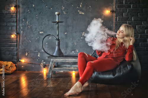 girl smokes hookah / beautiful glamorous girl in red dress smokes a hookah, the sexy model in a night club smokes