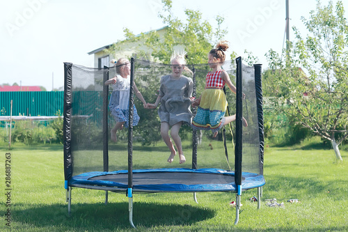 children jumping on a trampoline, girlfriends having fun in the summer in a recreation park on a trampoline