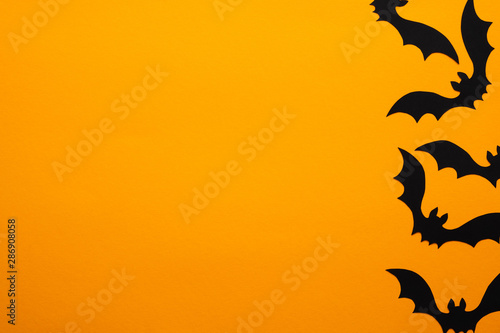 Happy halloween holiday concept. Halloween bats on orange background. Halloween party greeting card mockup with copy space. Flat lay, top view, overhead.