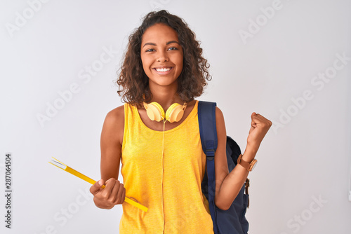 Brazilian student woman wearing backpack holding notebook over isolated white background screaming proud and celebrating victory and success very excited, cheering emotion