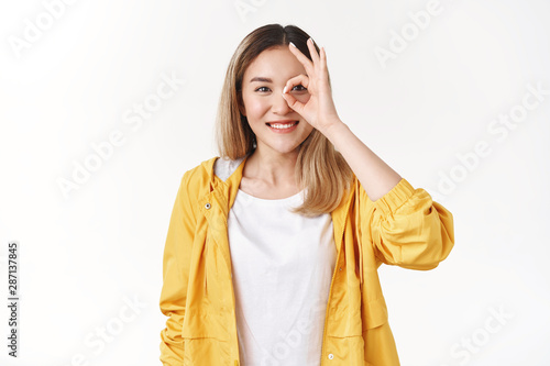 Positive silly optimistic modern asian blond girl happy smiling broadly enjoy sunny chilly summer evening show okay ok gesture assure everything perfect look through circle amused delighted