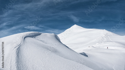 un lontano scialpinista si perde nel paesaggio invernale e immacolato