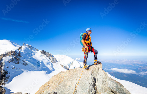 Alpinist mountaineer standing rock cliff mountain summit.