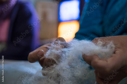 Woman with brushes preparing a wool for spining a woolen string for berber moroccan carpets