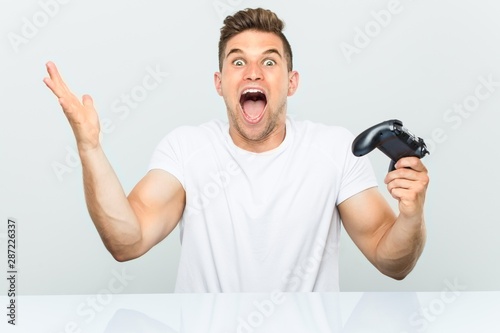 Young man holding a game controller celebrating a victory or success